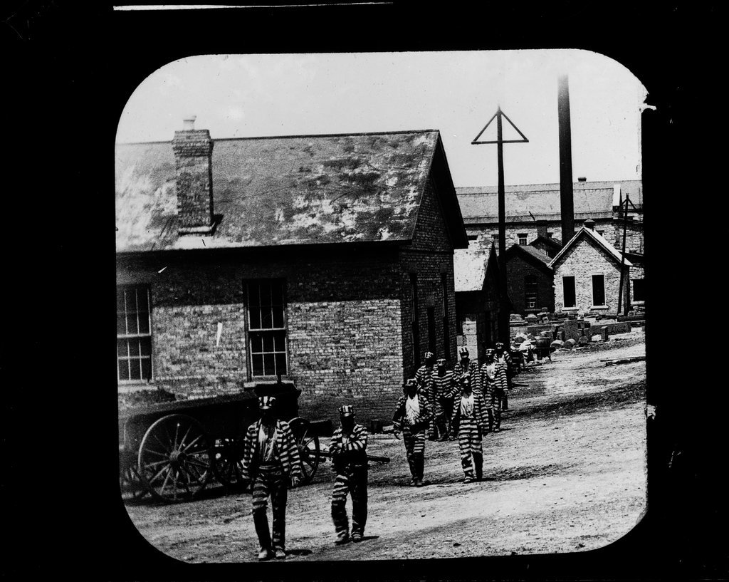 Imprisoned people marching by buildings - Wetmore, S. W.