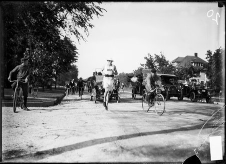 Athlete John Lindquist, running on a road during Illinois Athletic Club Marathon, large house is visible in the background - Chicago Daily News, Inc.