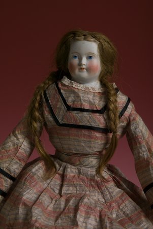 Bessie doll carried by Harriet Peabody Butler during escape from Chicago Fire (partial view of head and torso, red background)