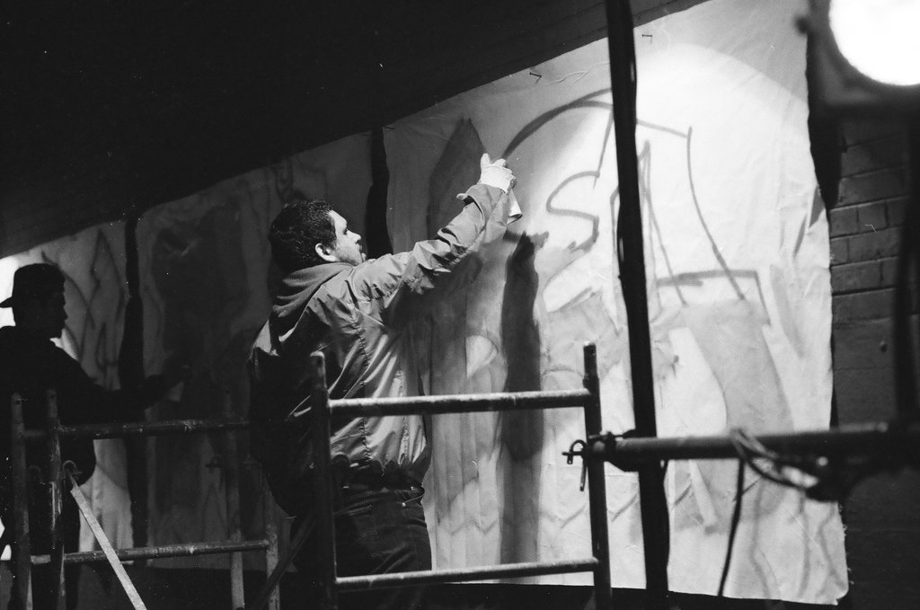 Young adults spray paint a wall with graffiti art - Chicago Sun-Times