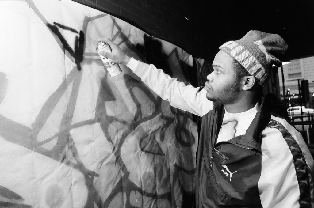 Young adults spray paint a wall with graffiti art - Chicago Sun-Times