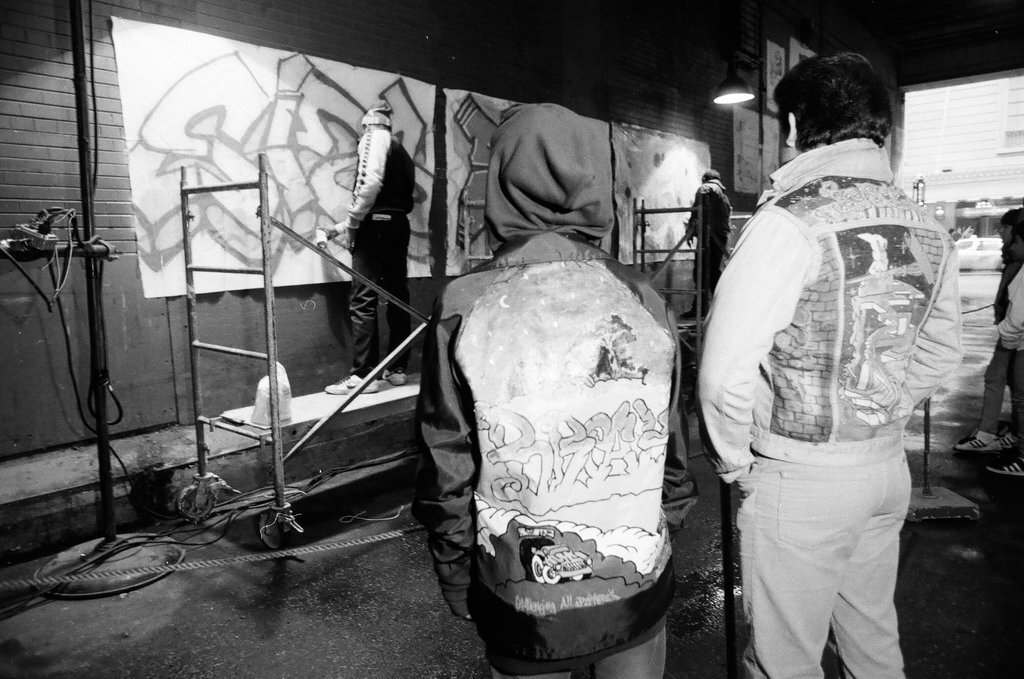 Young adults spray paint a wall with graffiti art - Chicago Sun-Times