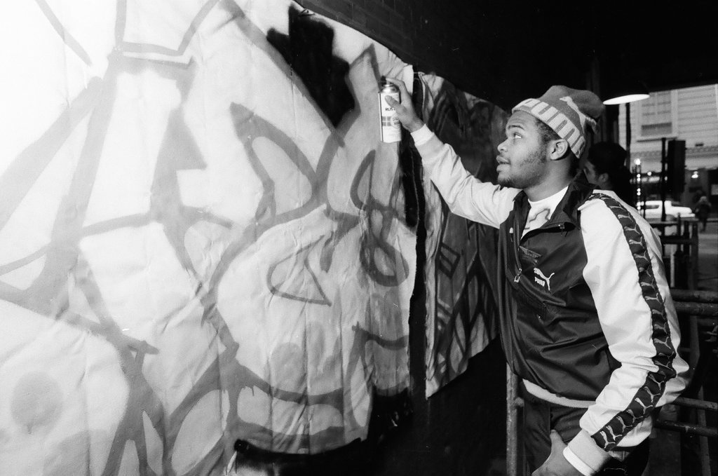 Young adults spray paint a wall with graffiti art - Chicago Sun-Times