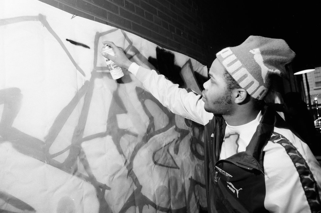 Young adults spray paint a wall with graffiti art - Chicago Sun-Times