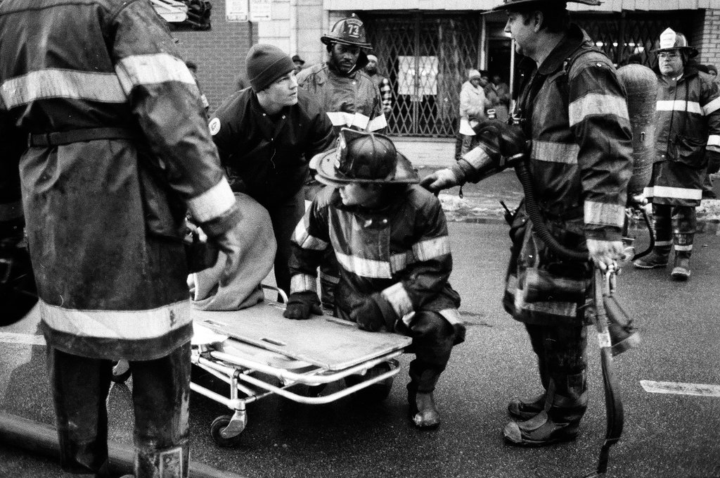 An injured fireman is loaded into an ambulance while remaining firefighters tackle a fire - Chicago Sun-Times