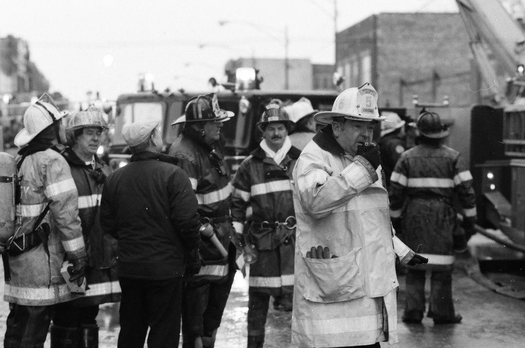 An injured fireman is loaded into an ambulance while remaining firefighters tackle a fire - Chicago Sun-Times