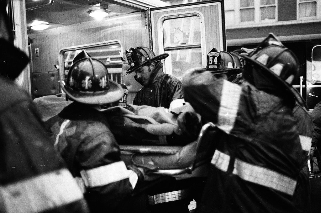 An injured fireman is loaded into an ambulance while remaining firefighters tackle a fire - Chicago Sun-Times