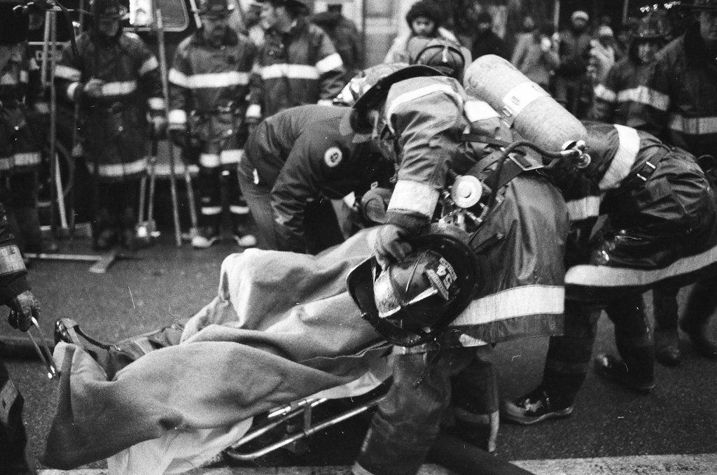 An injured fireman is loaded into an ambulance while remaining firefighters tackle a fire - Chicago Sun-Times