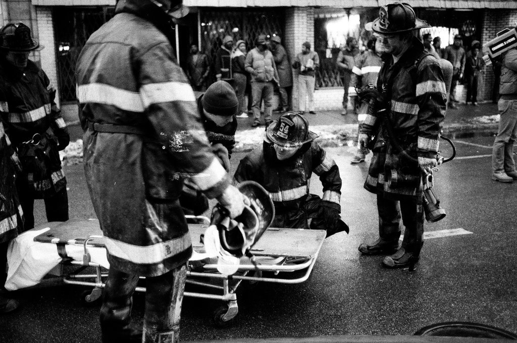 An injured fireman is loaded into an ambulance while remaining firefighters tackle a fire - Chicago Sun-Times