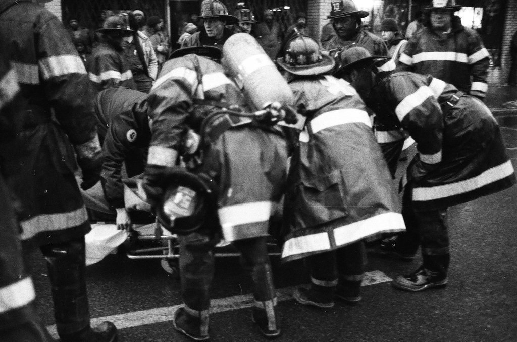 An injured fireman is loaded into an ambulance while remaining firefighters tackle a fire - Chicago Sun-Times