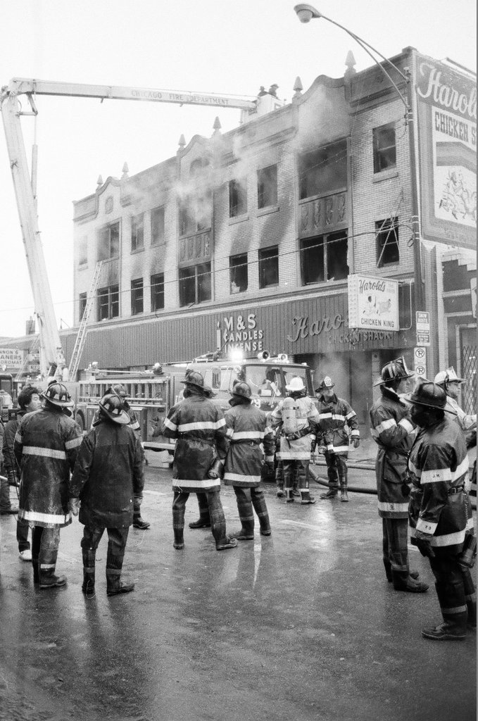 An injured fireman is loaded into an ambulance while remaining firefighters tackle a fire - Chicago Sun-Times