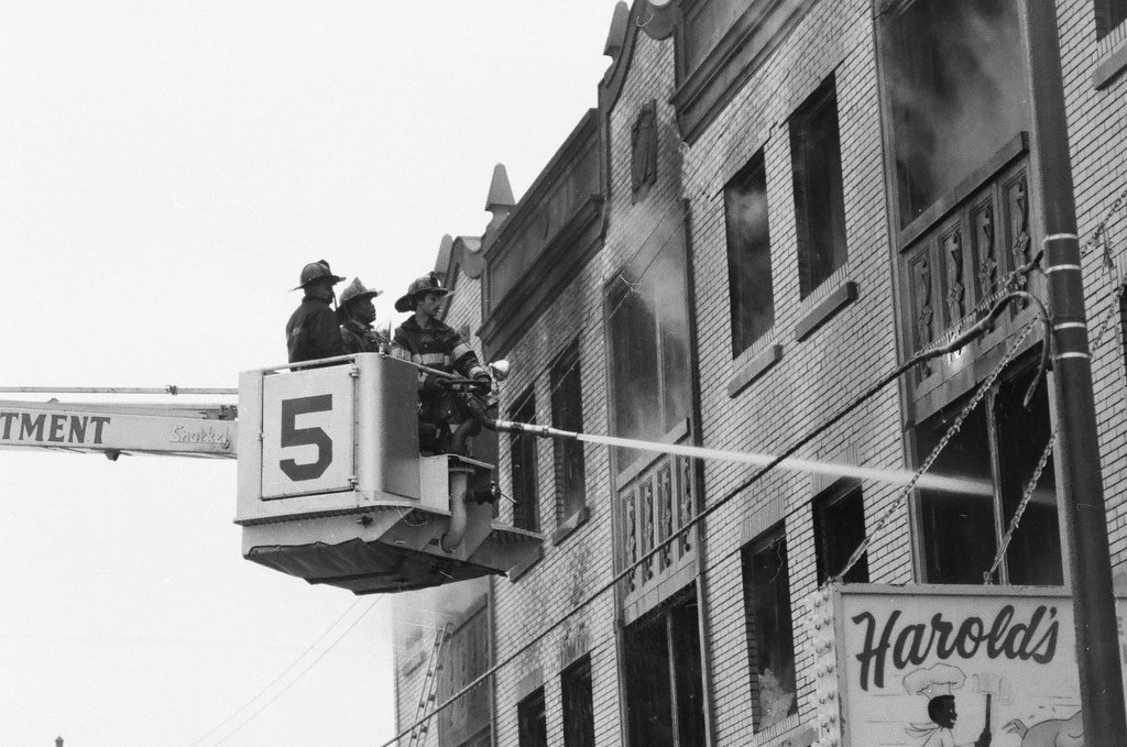 An injured fireman is loaded into an ambulance while remaining firefighters tackle a fire - Chicago Sun-Times