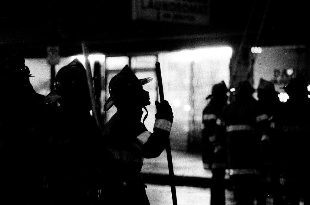 An injured fireman is loaded into an ambulance while remaining firefighters tackle a fire - Chicago Sun-Times